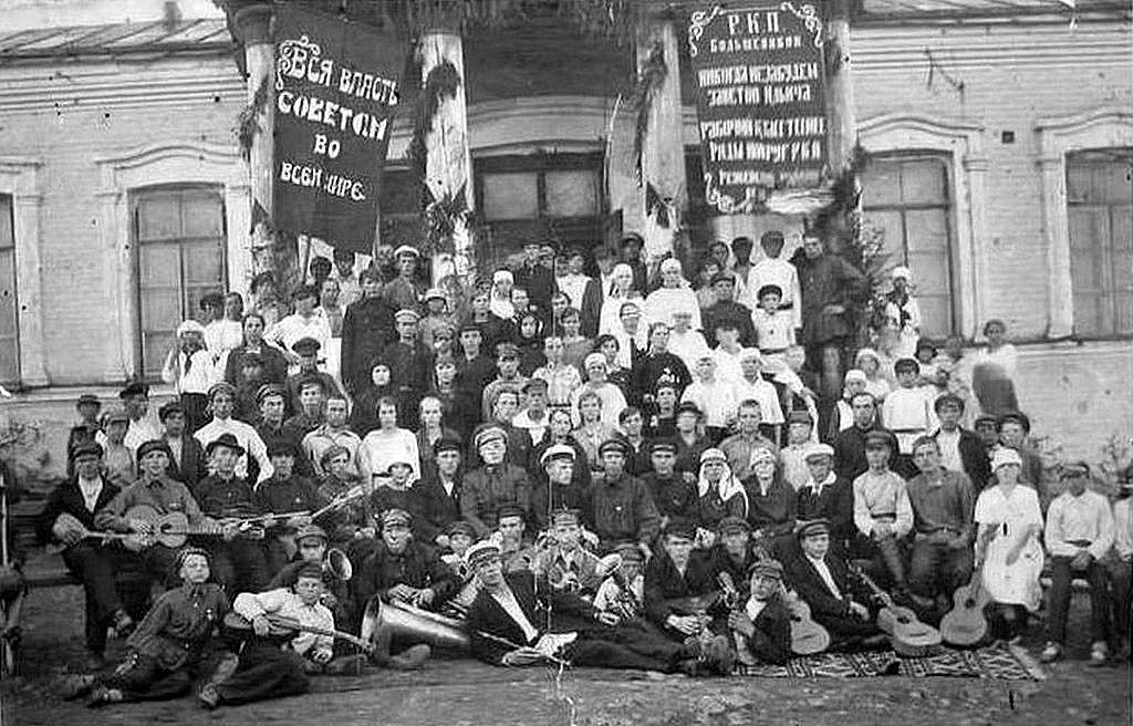 Фото 1920-х годов, коллектив художественной самодеятельности поселка Режевской завод, на заднем плане бывшее заводоуправление Режевского завода, в те годы клуб